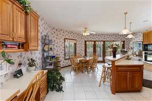 Kitchen with sink, ceiling fan, black microwave, stainless steel oven, and light tile floors