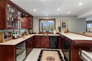 Kitchen featuring light colored carpet, kitchen peninsula, black dishwasher, wine cooler, and sink