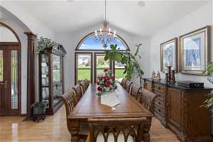Dining room featuring lofted ceiling, light hardwood / wood-style floors, ornate columns, and a wealth of natural light