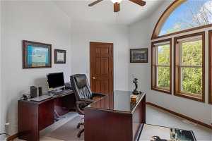 Home office featuring vaulted ceiling, ceiling fan, and carpet flooring