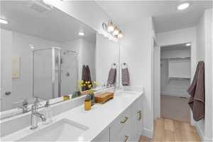 Bathroom featuring hardwood / wood-style floors, an enclosed shower, and dual vanity