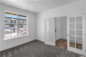 Unfurnished room with french doors and dark carpet