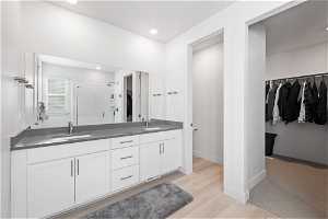 Bathroom featuring hardwood / wood-style flooring, dual sinks, an enclosed shower, and oversized vanity
