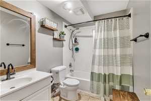Full bathroom with tile floors, vanity, shower / bath combination with curtain, and toilet
