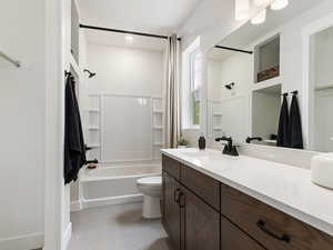 Full bathroom featuring vanity with extensive cabinet space, toilet, tile floors, and  shower combination