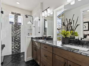 Bathroom featuring tile flooring, an enclosed shower, large vanity, and double sink