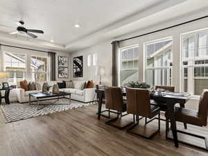 Dining room with dark hardwood / wood-style flooring, ceiling fan, and a tray ceiling