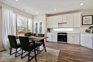 Kitchen with stainless steel stove, tasteful backsplash, light wood-type flooring, white cabinets, and sink