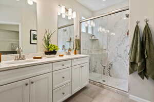 Bathroom featuring tile floors, walk in shower, double sink, and vanity with extensive cabinet space