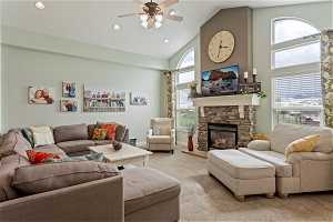 Living room featuring high vaulted ceiling, ceiling fan, a fireplace, and carpet floors