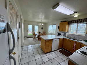 Kitchen with kitchen peninsula, a healthy amount of sunlight, and white appliances