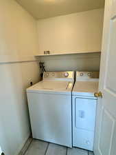 Laundry area featuring a textured ceiling, washing machine and dryer, and light tile floors