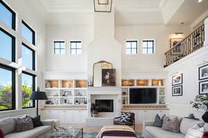 Living room with ornamental molding, wood-type flooring, a high ceiling, and a wealth of natural light