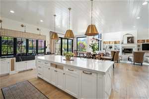 Kitchen with white cabinets, pendant light fixtures, light hardwood / wood-style flooring, and a center island