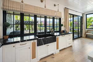 Kitchen featuring sink, light hardwood / wood-style flooring, pendant light fixtures, and white cabinetry