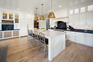 Kitchen with a center island, tasteful backsplash, white cabinetry, a breakfast bar area, and decorative light fixtures