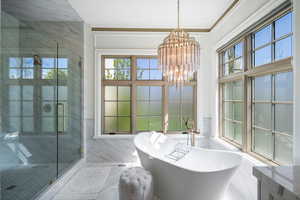 Bathroom featuring tile walls, ornamental molding, an inviting chandelier, tile flooring, and independent shower and bath