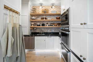 Bar with appliances with stainless steel finishes, light hardwood / wood-style flooring, sink, and white cabinets