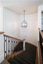 Staircase with hardwood / wood-style flooring and an inviting chandelier