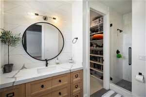 Bathroom with tile walls, a shower with shower door, and vanity