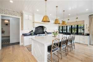 Kitchen with backsplash, light hardwood / wood-style flooring, a breakfast bar area, and pendant light fixtures
