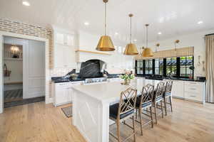 Kitchen with backsplash, light hardwood / wood-style flooring, a breakfast bar area, and pendant light fixtures