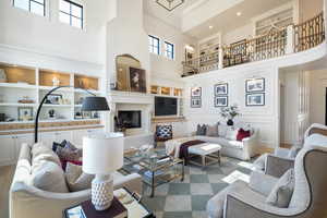 Living room with built in shelves, wood-type flooring, a towering ceiling, and a large fireplace