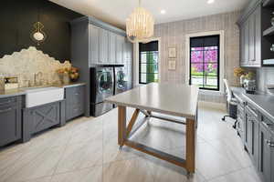 Kitchen featuring pendant lighting, light tile flooring, washer and clothes dryer, gray cabinetry, and an inviting chandelier