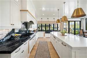 Kitchen with backsplash, pendant lighting, white cabinets, and a center island