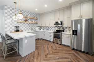 Kitchen with lvp flooring, tasteful backsplash, appliances with stainless steel finishes, and kitchen peninsula