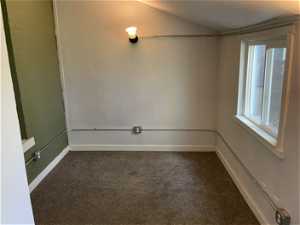 Unfurnished room with lofted ceiling, carpet flooring, and a wealth of natural light