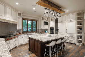 Kitchen featuring a center island, recessed lighting, open shelves, appliances with stainless steel finishes, and a breakfast bar area