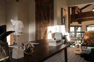 Home office featuring beamed ceiling, ceiling fan, and wood finished floors