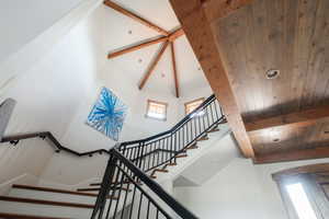 Staircase with high vaulted ceiling and a wooden ceiling with exposed beams