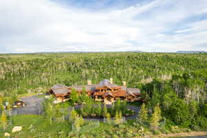 Aerial view of property and surrounding area featuring a forest