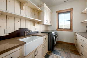 Laundry room with independent washer and dryer, cabinet space, and stone tile flooring