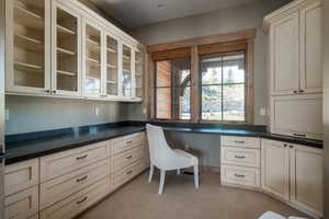 Unfurnished office featuring built in study area and light colored carpet