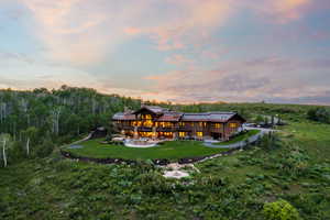 Rear view of house with a lawn, an outdoor fire pit, a chimney, a wooden deck, and a patio