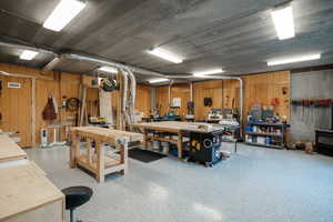 Garage featuring a workshop area, a wood stove, and wooden walls