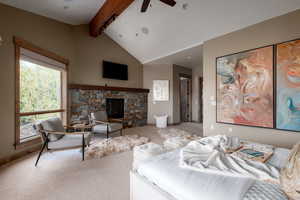 Living room with ceiling fan, carpet floors, and a stone fireplace