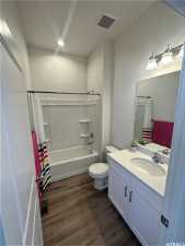 Full bathroom with hardwood / wood-style flooring, toilet, shower / bath combo, and vanity with extensive cabinet space