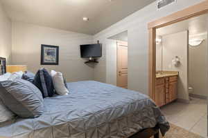 Bedroom with sink, ensuite bathroom, and light tile floors