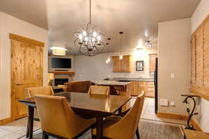 Dining area with a chandelier, sink, a tiled fireplace, and light tile flooring