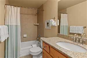 Full bathroom featuring tile floors, oversized vanity, toilet, and shower / tub combo with curtain