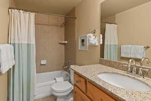 Full bathroom featuring tile floors, oversized vanity, toilet, and shower / tub combo with curtain