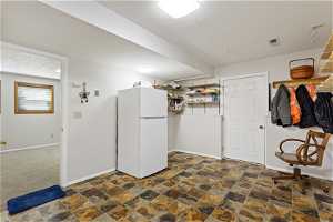 Interior space featuring white refrigerator and dark tile flooring