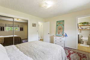 Bedroom featuring ensuite bath, tile floors, a closet, and a textured ceiling