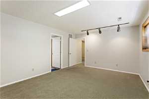 Empty room with rail lighting, carpet floors, and a textured ceiling