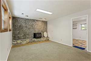 Unfurnished living room with a wood stove, carpet, and a textured ceiling