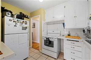 Kitchen featuring white cabinets, white appliances, backsplash, and light tile floors